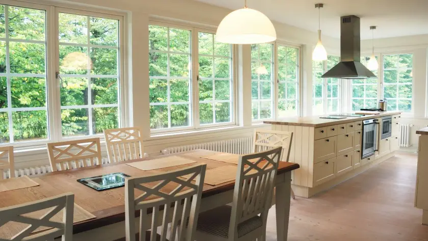 Table and chairs in a brightly lit dining room with large composite windows