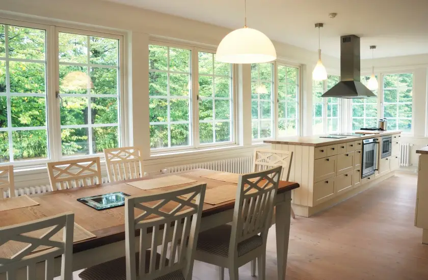 Table and chairs in a brightly lit dining room with large composite windows