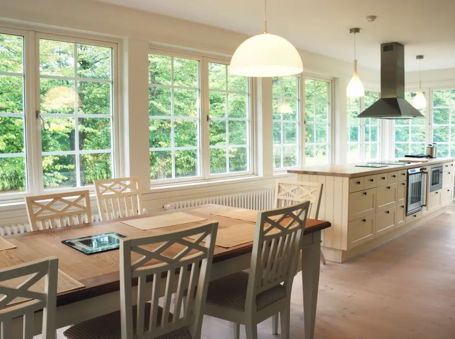 Table and chairs in a brightly lit dining room with large composite windows