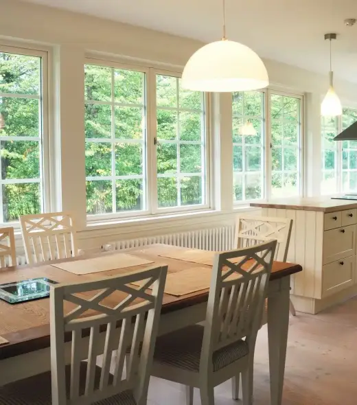 Table and chairs in a brightly lit dining room with large composite windows